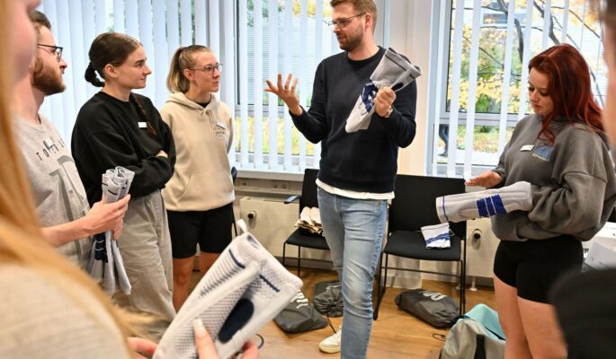 Die Rahm-Auszubildenden verfolgen, was ihnen Trainer Mattis Hohmann von der Bauerfeind-Akademie zum Thema Kniebandagen erklärt. (Foto: Bauerfeind)